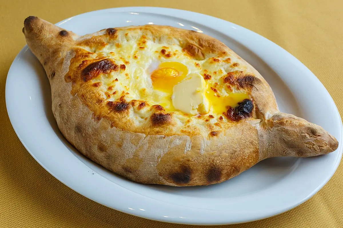 A boat-shaped Adjarian khachapuri filled with melted cheese, an egg yolk and butter