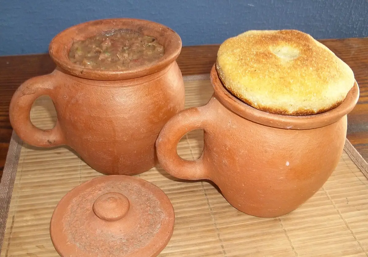 Bean stew in clay pots, one covered with a round of cornbread