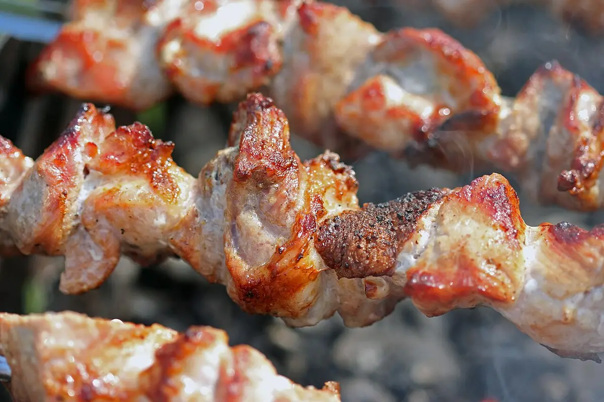 Skewers of pork grilling over hot coals