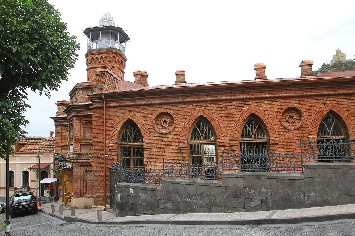 The red-brick Juma Mosque with pointed arched windows and a slim minaret