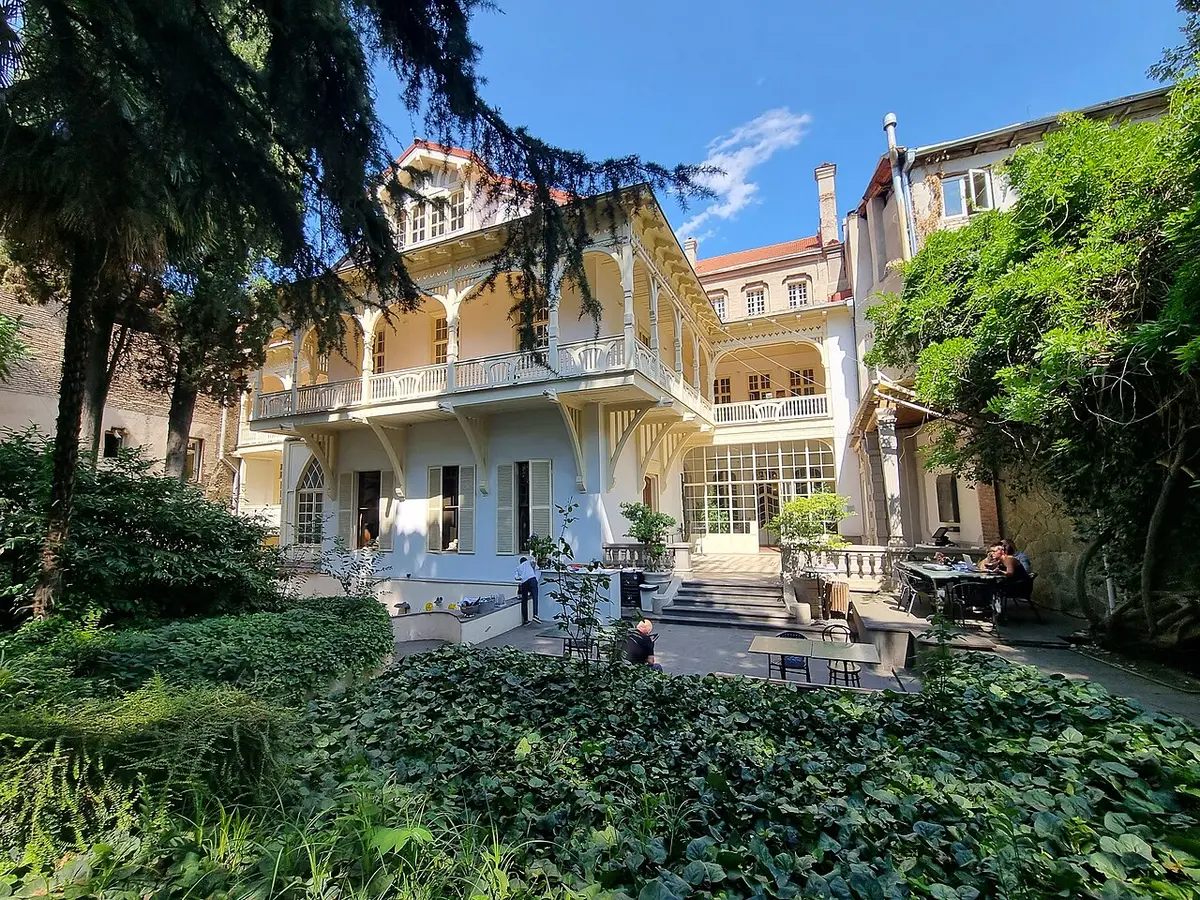 The Writers’ House of Georgia, a pale mansion with balconies, seen across its green garden