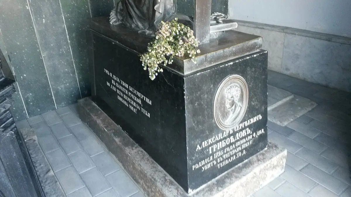Griboyedov’s black stone tomb with a bronze portrait medallion and Russian inscriptions, flowers on top