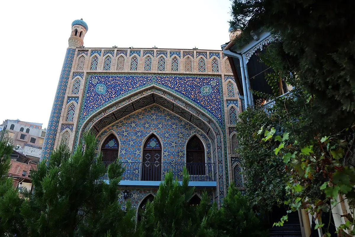The blue-tiled facade of Chreli Abano, the Orbeliani baths, with a pointed arch and a small tower at the corner