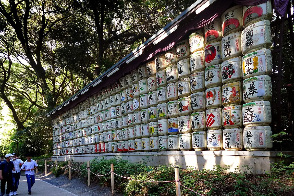 Rows of decorated sake barrels stacked beside a path at Meiji Jingu