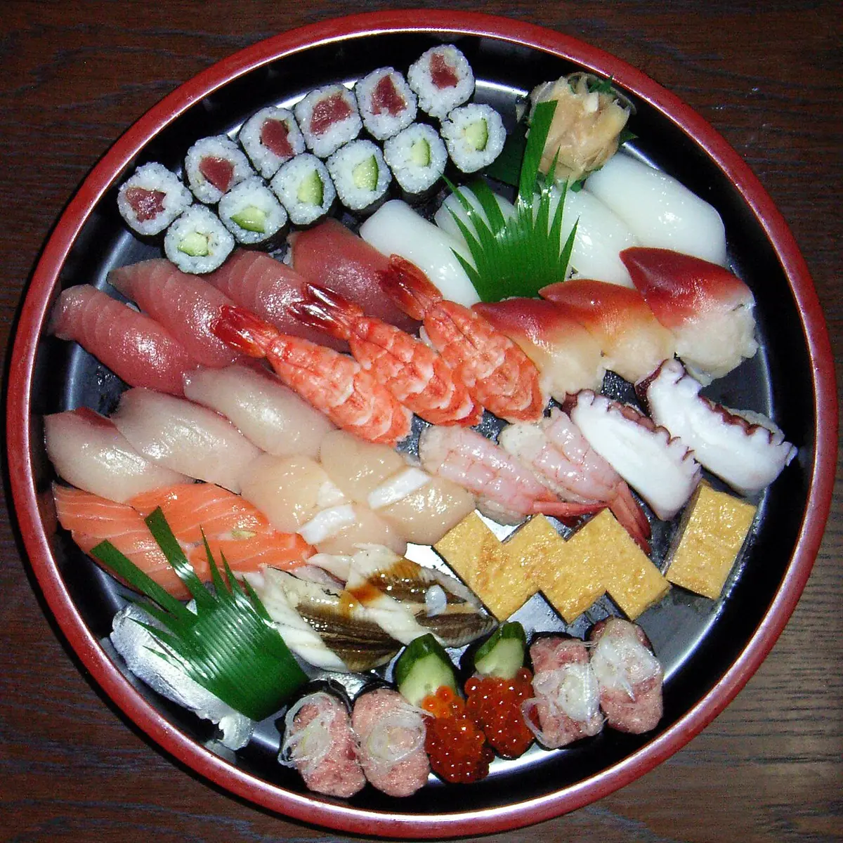 A round lacquered tray of nigiri sushi and rolls