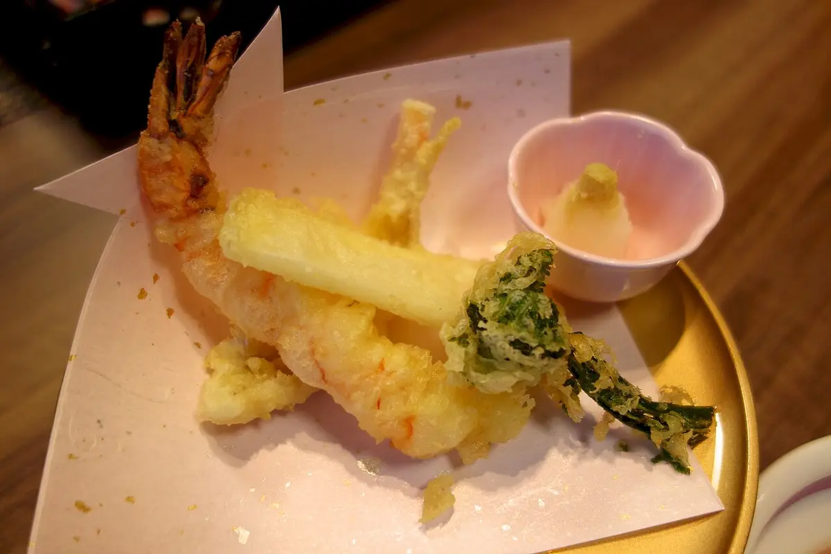 Shrimp and vegetable tempura on paper, with a dish of grated radish
