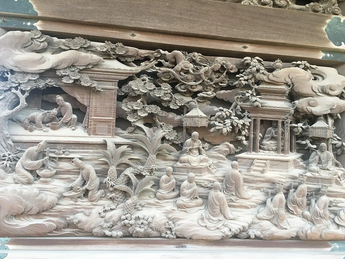 A carved wooden panel at Shibamata Taishakuten showing monks and pavilions among pines and clouds