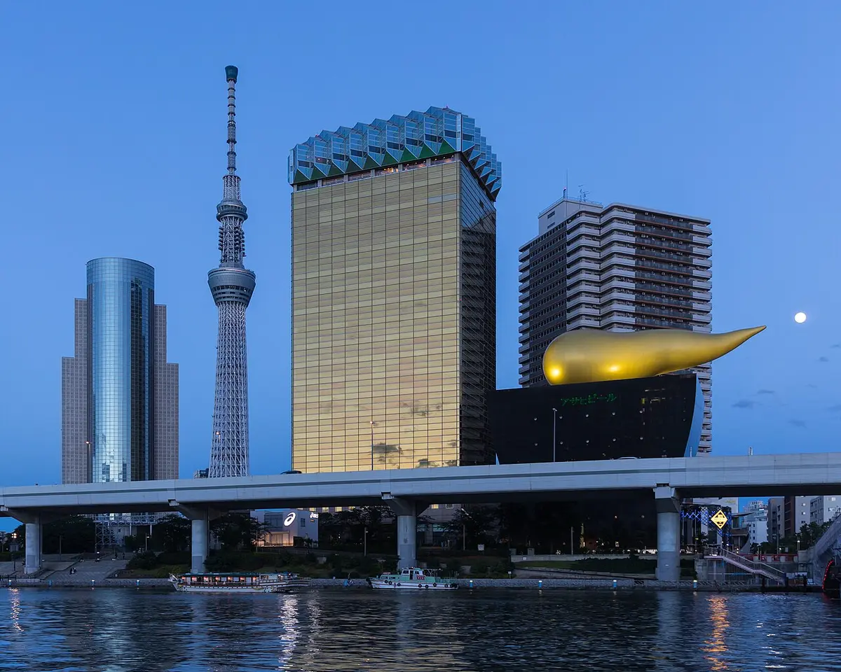 Tokyo Skytree at dusk beside the golden Asahi headquarters and its flame sculpture, a full moon above
