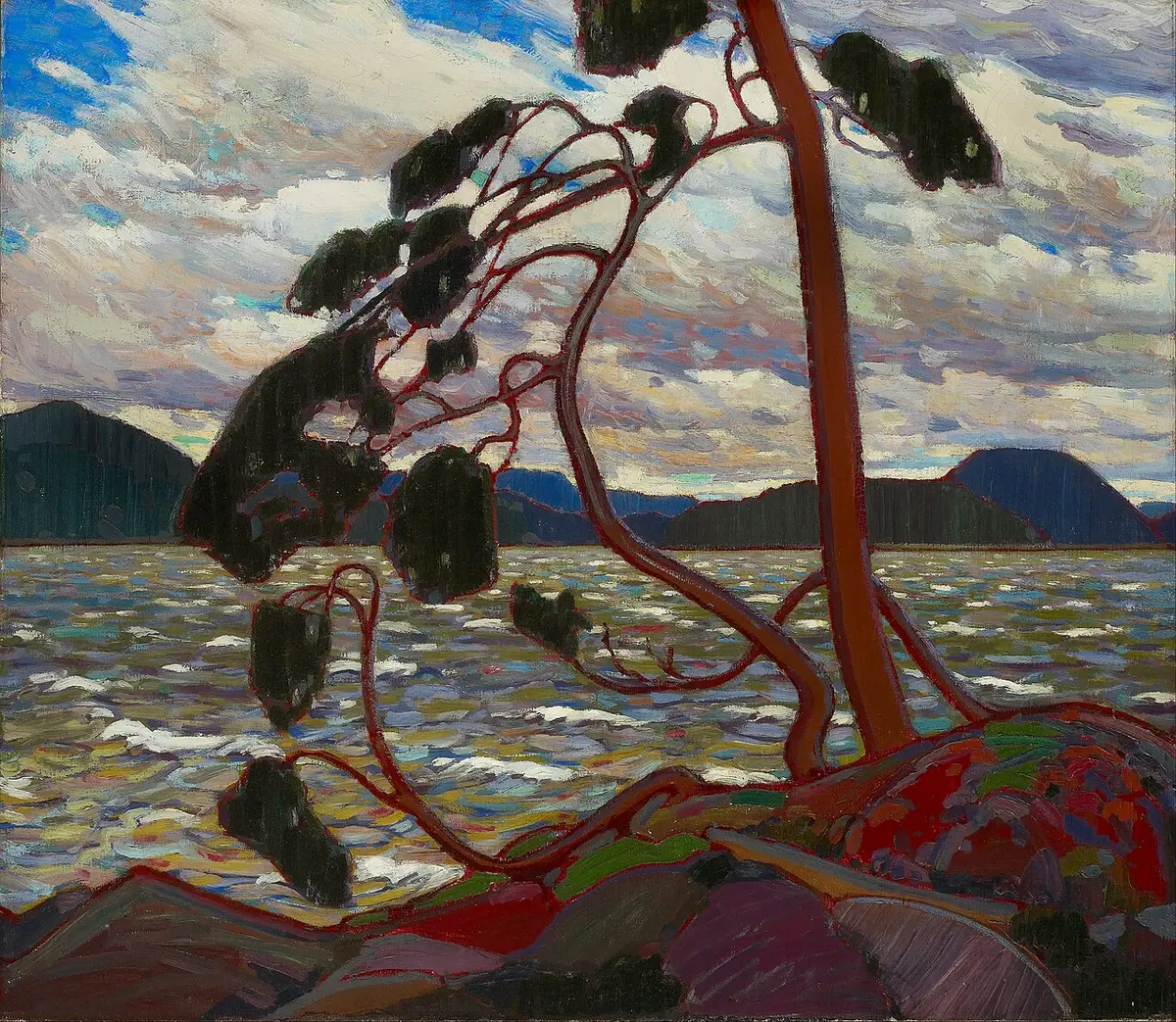 Tom Thomson painting of a windswept pine on a rocky shore above a choppy lake