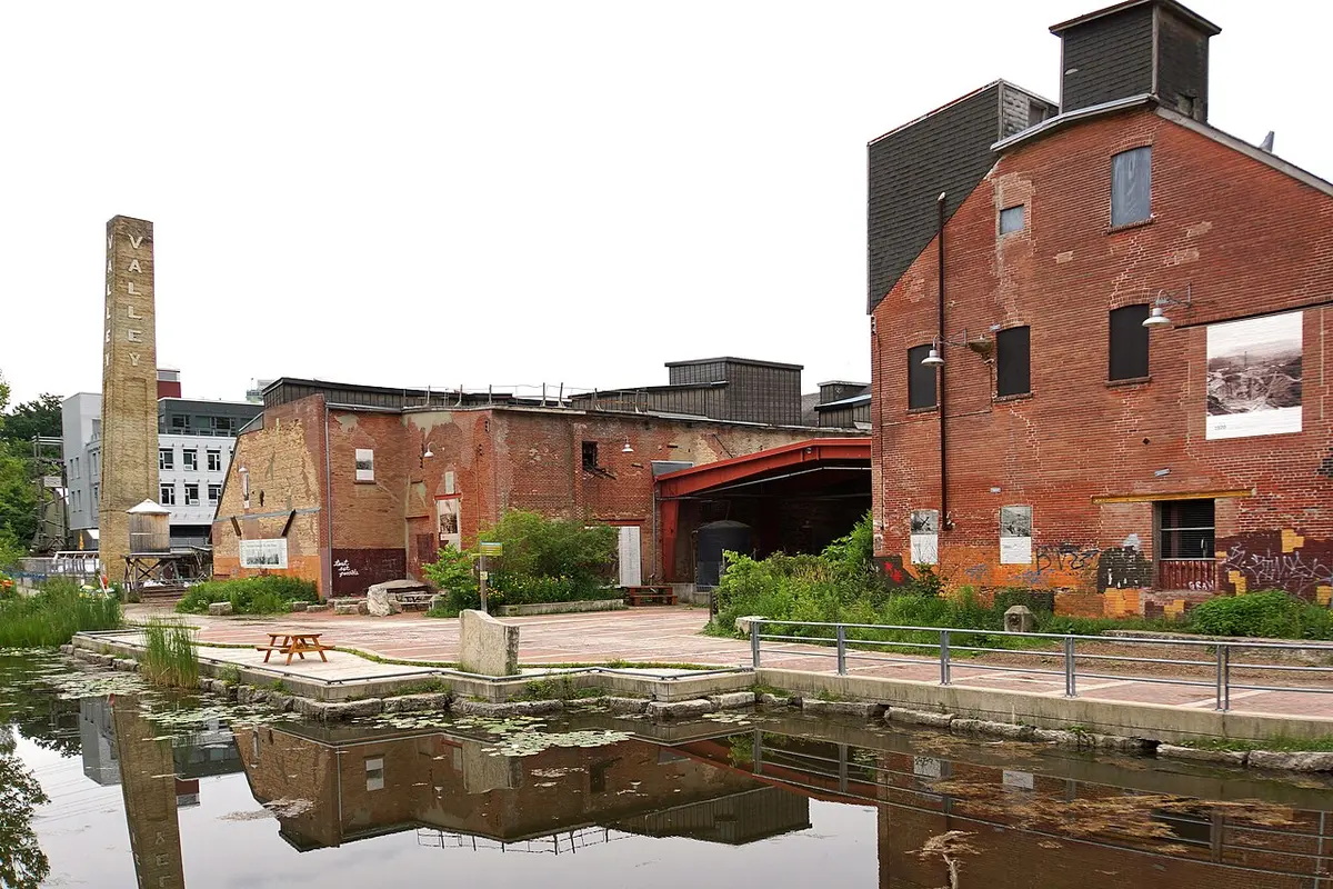 Old brick factory buildings and a tall chimney reflected in a pond at Evergreen Brick Works