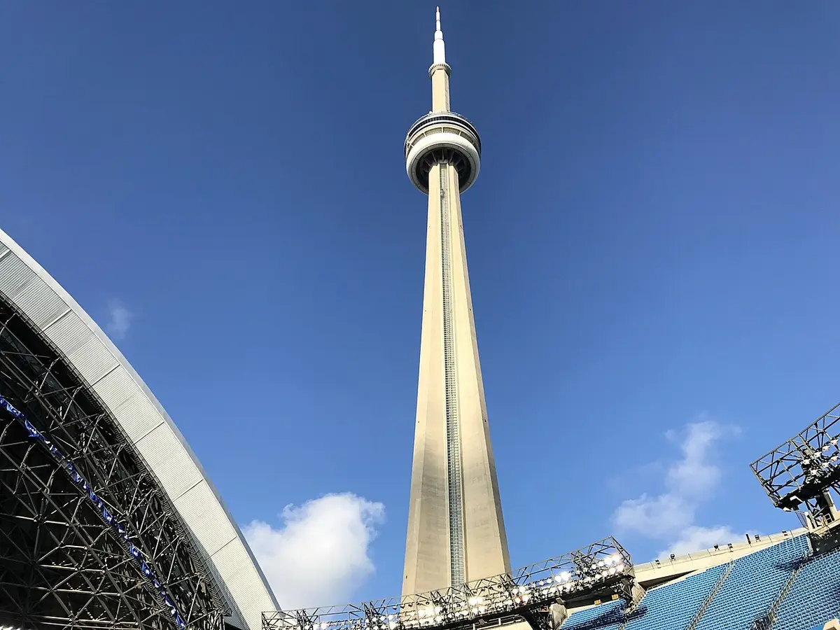 The CN Tower rising into a blue sky, seen from inside the stadium at its foot