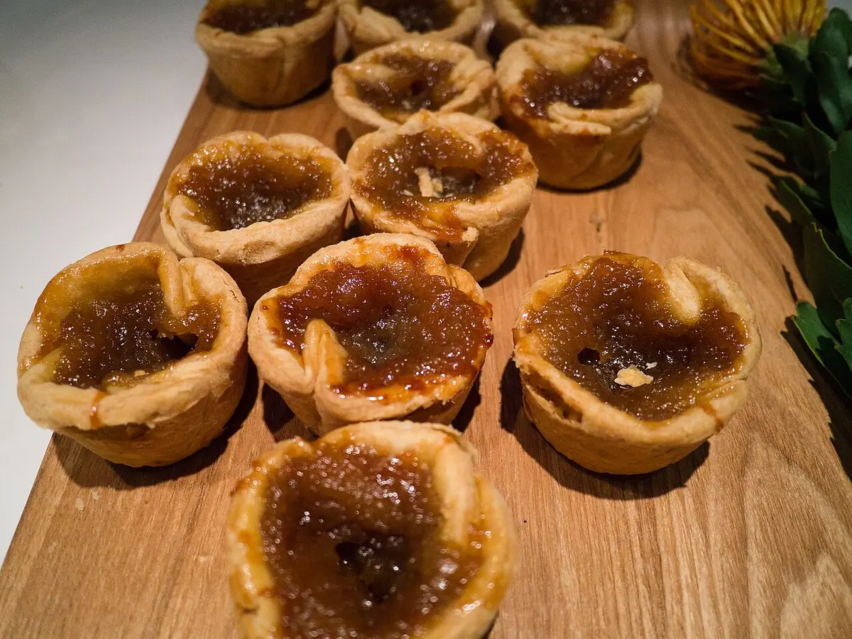 Butter tarts with golden filling on a wooden board