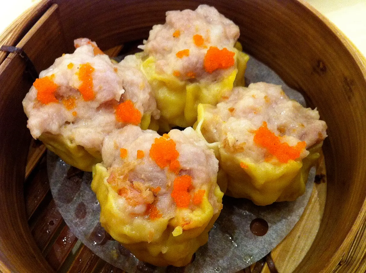Pork and shrimp dumplings topped with orange roe in a bamboo steamer