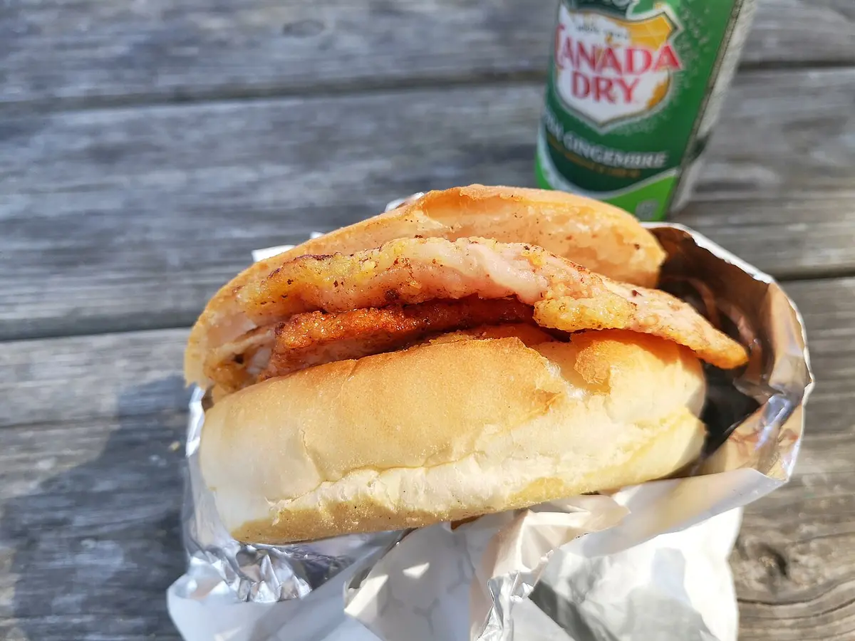 A peameal bacon sandwich on a soft bun, wrapped in foil, from Carousel Bakery