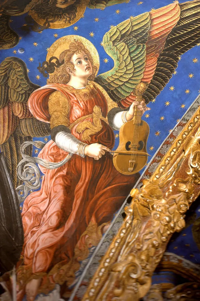 Fresco of an angel with green and gold wings in a red robe, playing a bowed viol against a starry blue sky