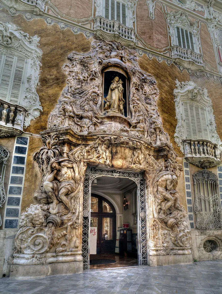 The carved alabaster portal of the Dos Aguas palace, two giant figures pouring water beside the door and a Virgin in a niche above
