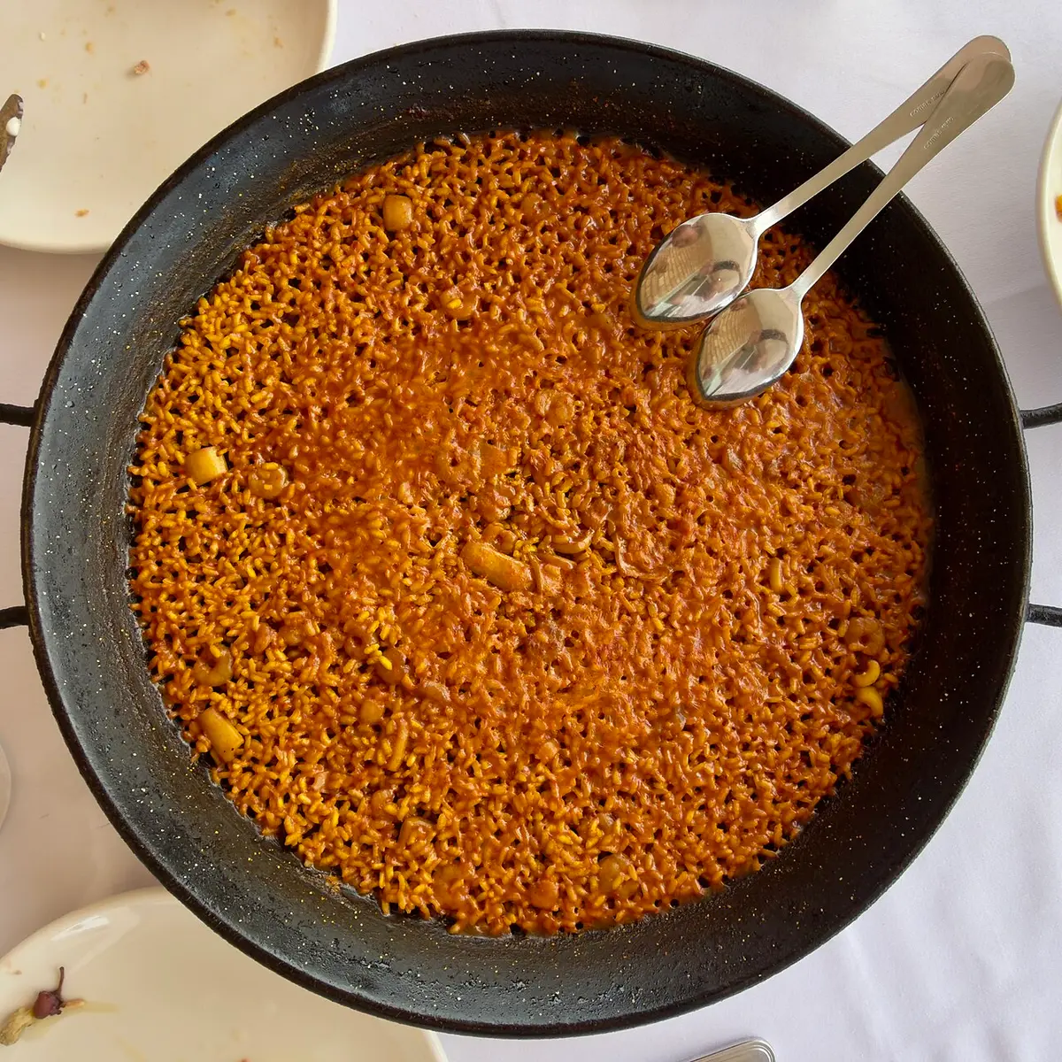 A pan of arròs a banda, golden rice cooked in fish stock, with two spoons