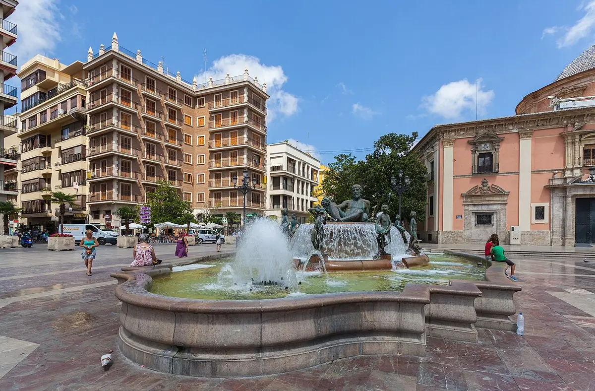 The Turia fountain in the Plaza de la Virgen, a reclining bronze figure among jets of water, the basilica on the right