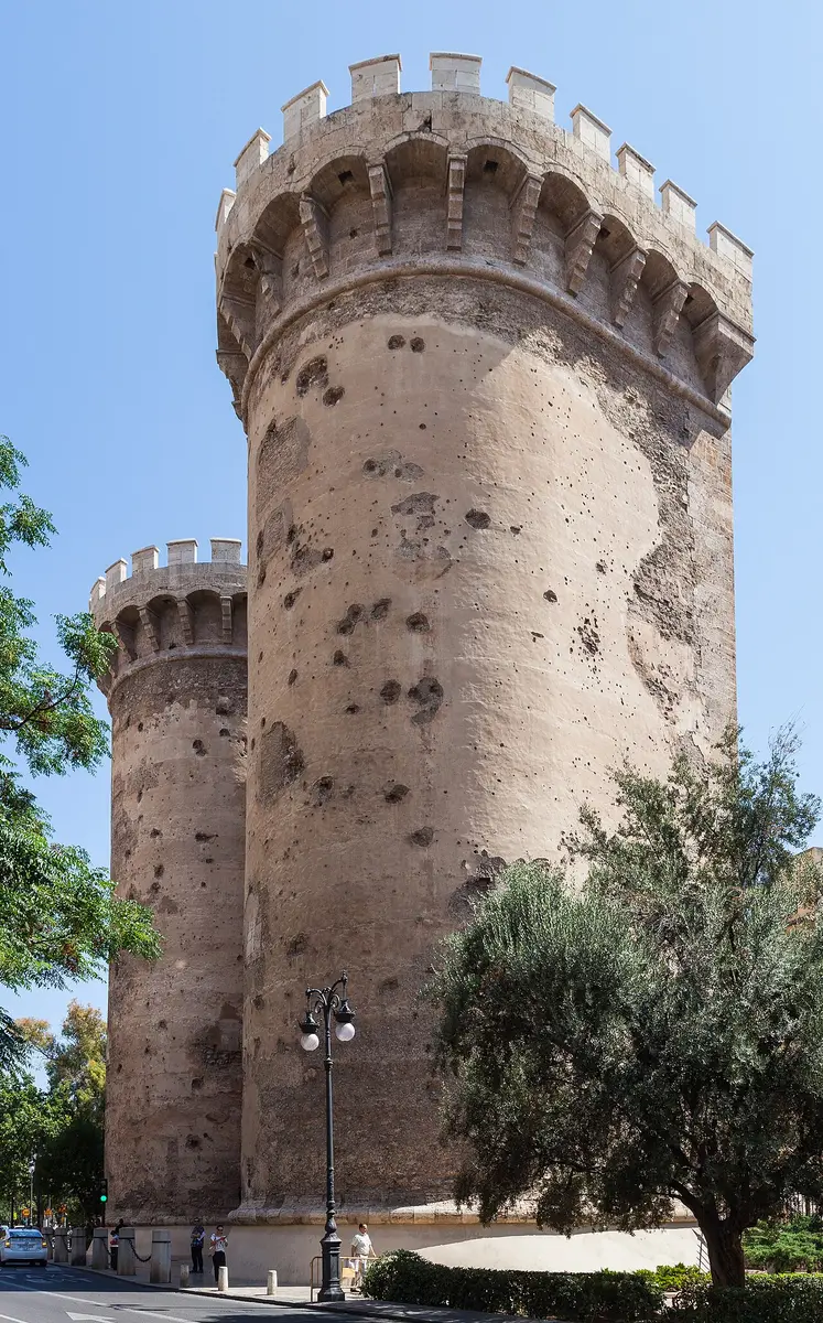 A round crenellated tower of the Quart gate, its stone pitted with the marks of cannonballs and musket fire