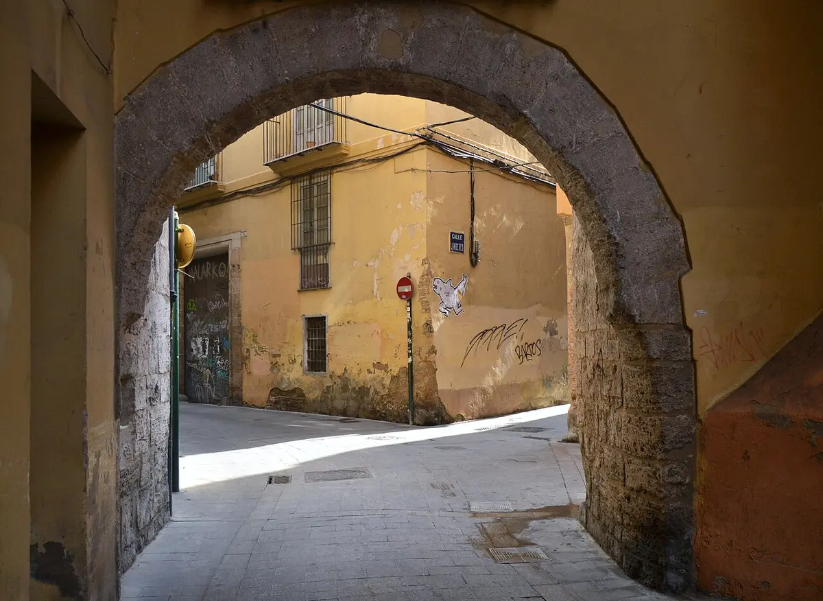 A low stone arch over a narrow lane of ochre houses in the old town